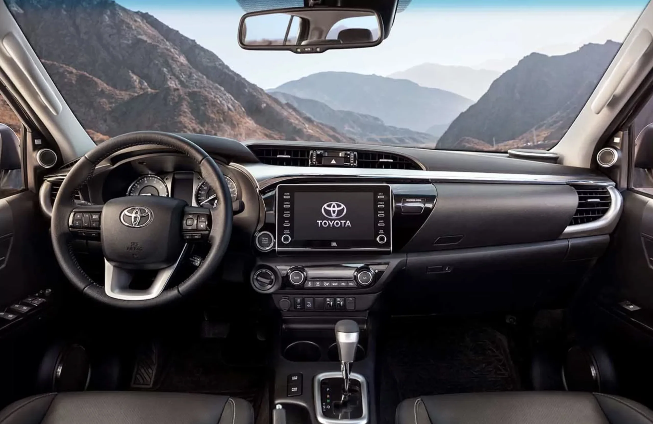 Interior da Hilux SRX 2.8 foca conforto diário, com espaço para cinco, bancos em couro, ar digital de duas zonas e tecnologia que ajuda em viagens longas.