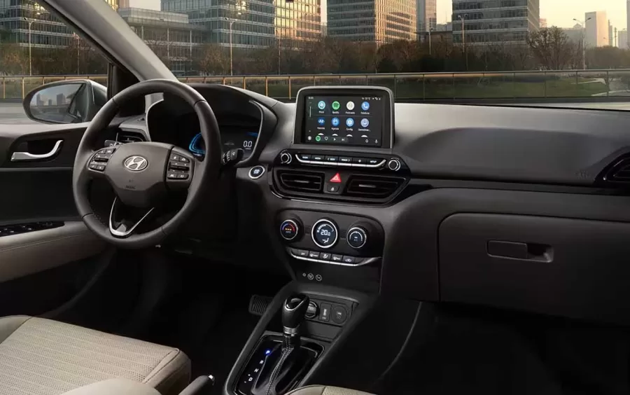 O interior do HB20S é simples, com plásticos duros, mas inclui detalhes em couro sintético em tom claro. A central multimídia oferece conectividade sem fio para Android Auto e Apple CarPlay.