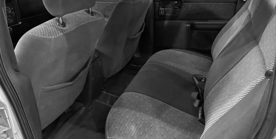 A cabine dupla acomoda cinco ocupantes, com interior simples, caçamba de 860 litros e carga útil de 810 kg, voltada ao transporte de carga e uso misto.