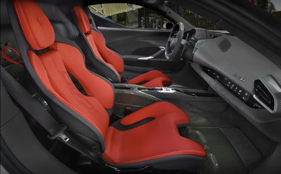 O interior é quase monástico. Kevlar cru, Alcantara cinza e tecido vermelho técnico transformam o cockpit num santuário de corrida, onde estética e desempenho brigam pela mesma atenção.