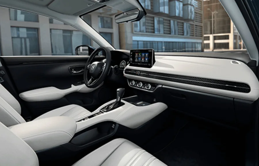 A cabine traz bancos de couro, painel horizontal com textura de colmeia e multimídia de 9”, integrando conforto e conectividade sem fio.