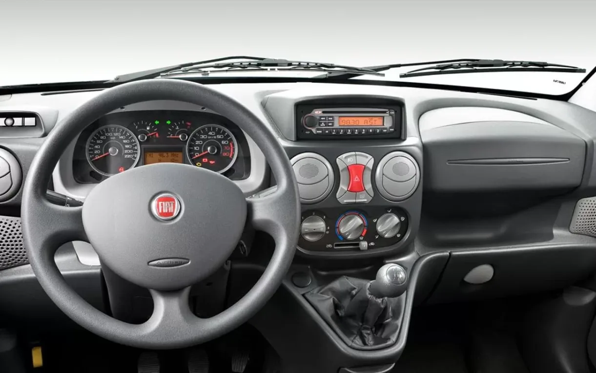 A cabine é simples, mas funcional, com posição de dirigir elevada, boa visibilidade e espaço interno favorecido pela carroceria alta da minivan.