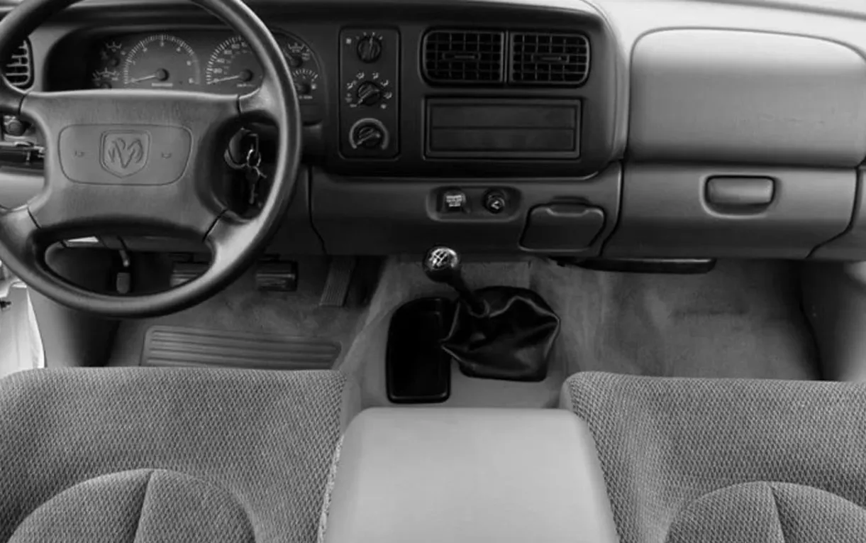 A cabine leva 2 pessoas, tem acabamento simples e foco no trabalho, enquanto a estrutura favorece quem precisa carregar ferramenta e material.