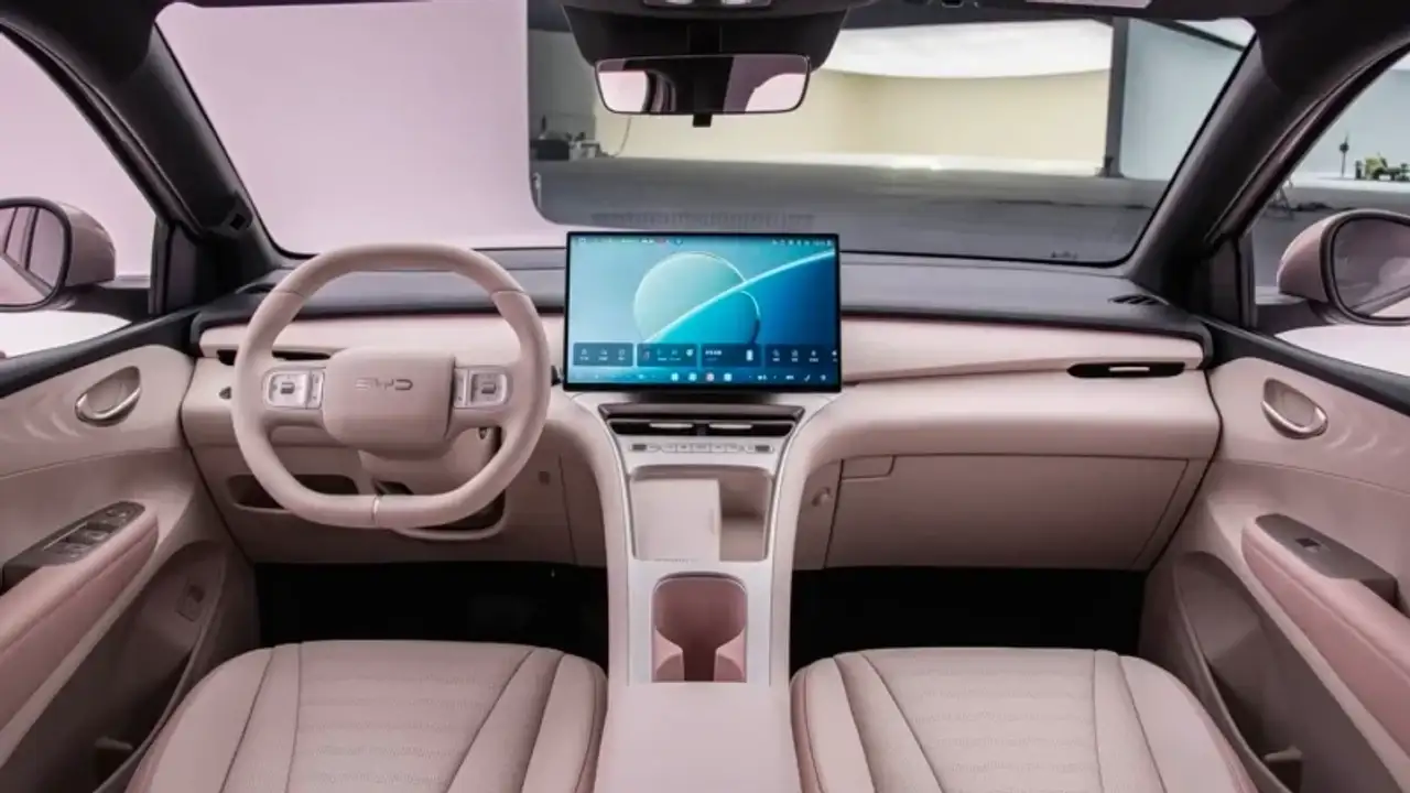 O interior muda bastante. Há volante de dois raios, tela central flutuante, carregador de celular sem fio e botões físicos abaixo das saídas de ar-condicionado.